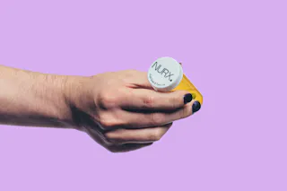 Hand holding a yellow prescription bottle with a white cap, labeled 