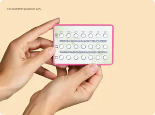 Hands holding a pink-bordered birth control pill pack with labeled days of the week.
