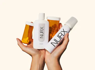 Hands holding four medicine bottles, two are pill containers and two are labeled 