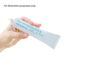A hand holding a tube of metronidazole vaginal gel, 0.75%.