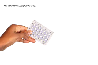 A person holds a blister pack of pills against a white background.
