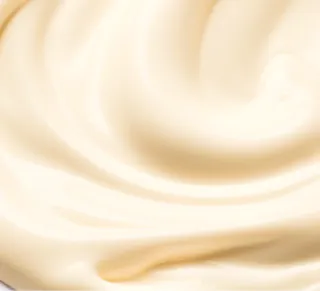 A close-up of a smooth, creamy white substance, much like tretinoin cream, evenly spread with soft swirls and a shiny texture.