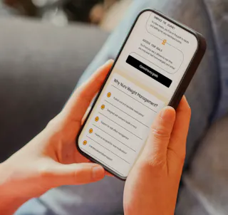 A person is holding a smartphone displaying a webpage about weight management, with a list of benefits and a 